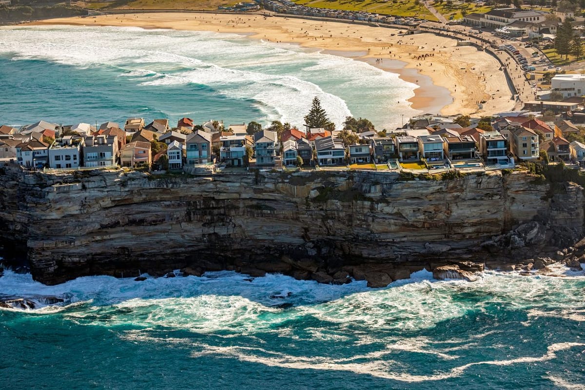 Cliffside homes overlooking a beach and ocean waves.