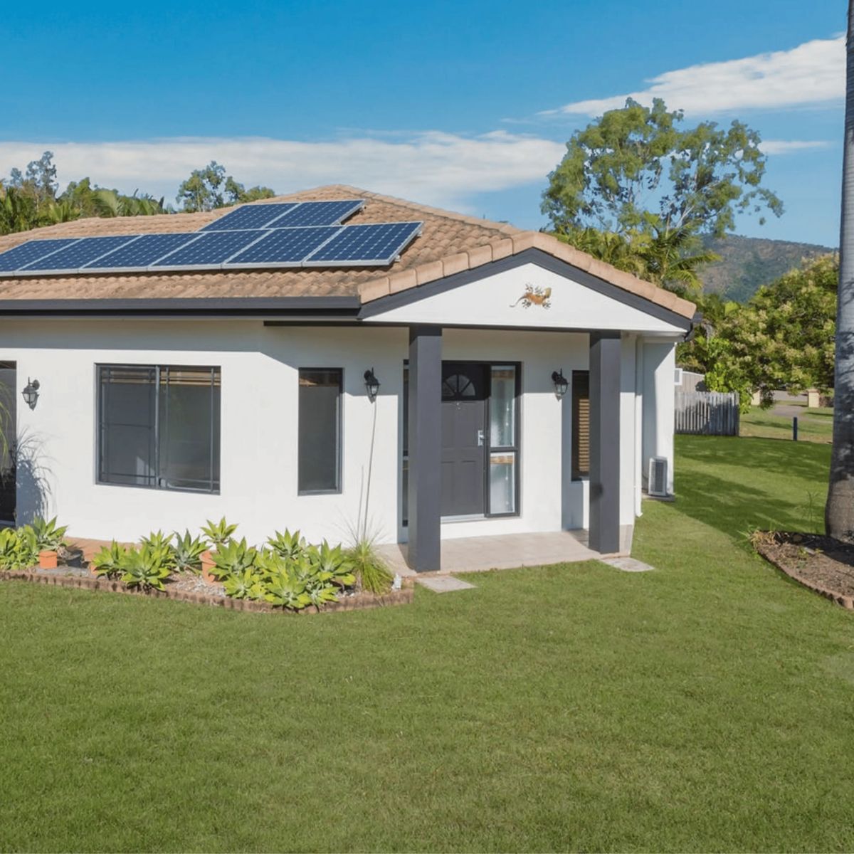 White house with solar panels and green lawn.
