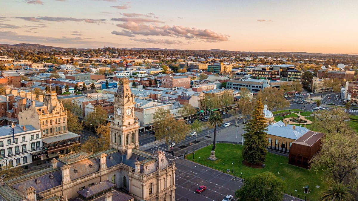 Town square with clock tower and park at sunset.
