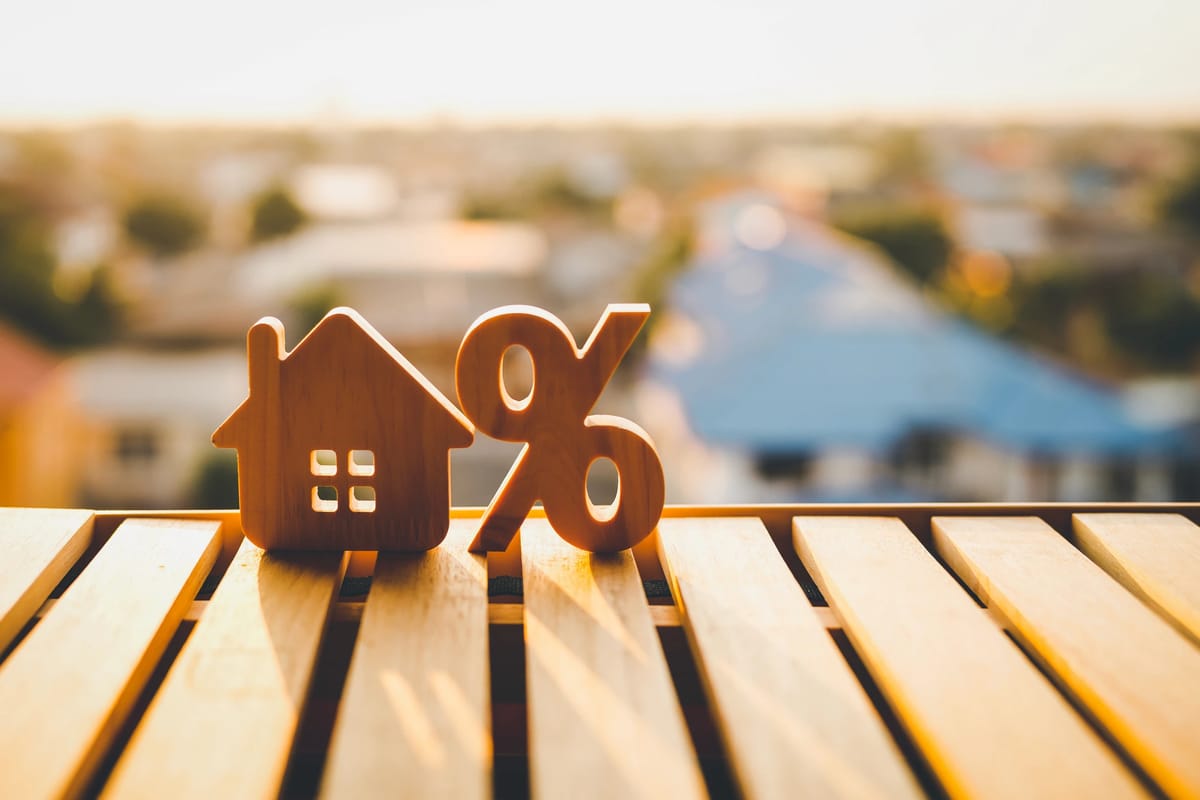 Wooden house and percentage symbols overlooking a suburban neighbourhood
