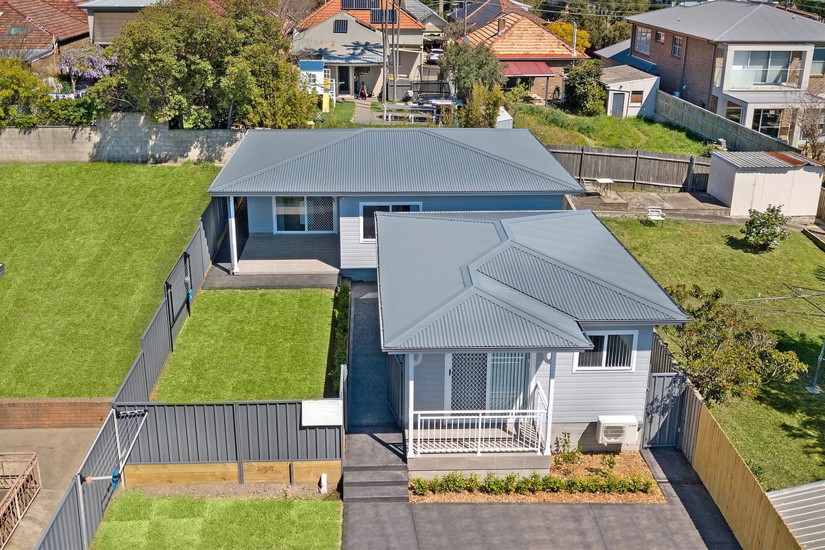 Two modern grey houses with green lawns.