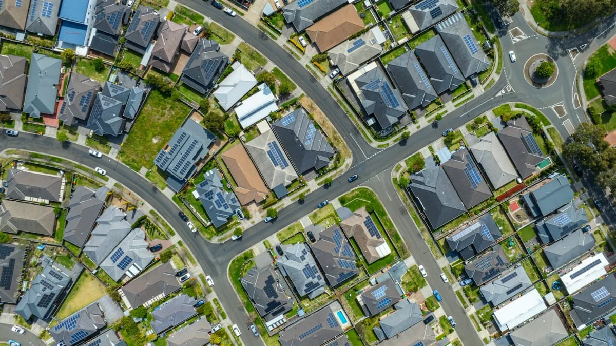Aerial view of suburban houses with solar panels.