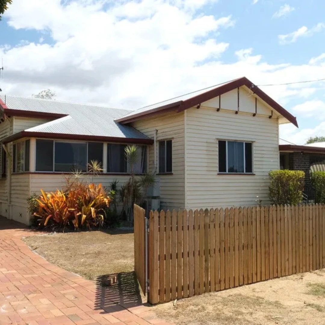 Cream-colored house with a picket fence and red roof.