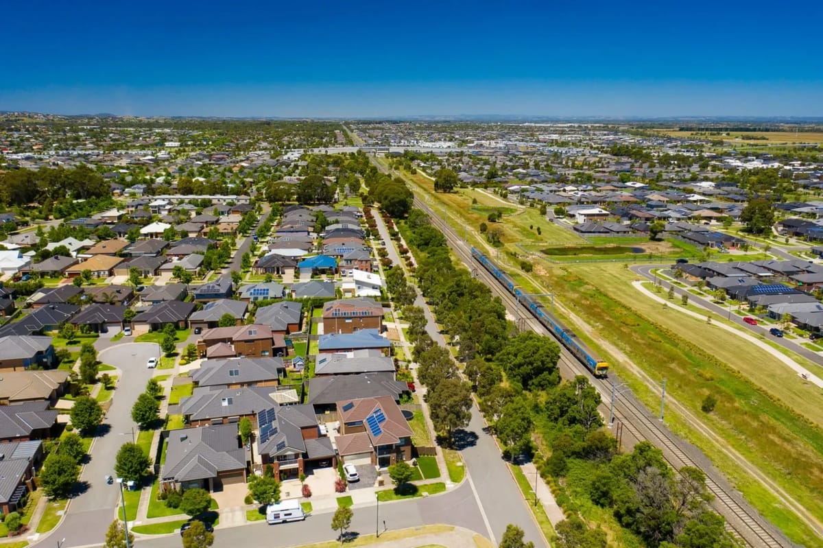 Aerial view of suburban homes beside a major road and rail corridor