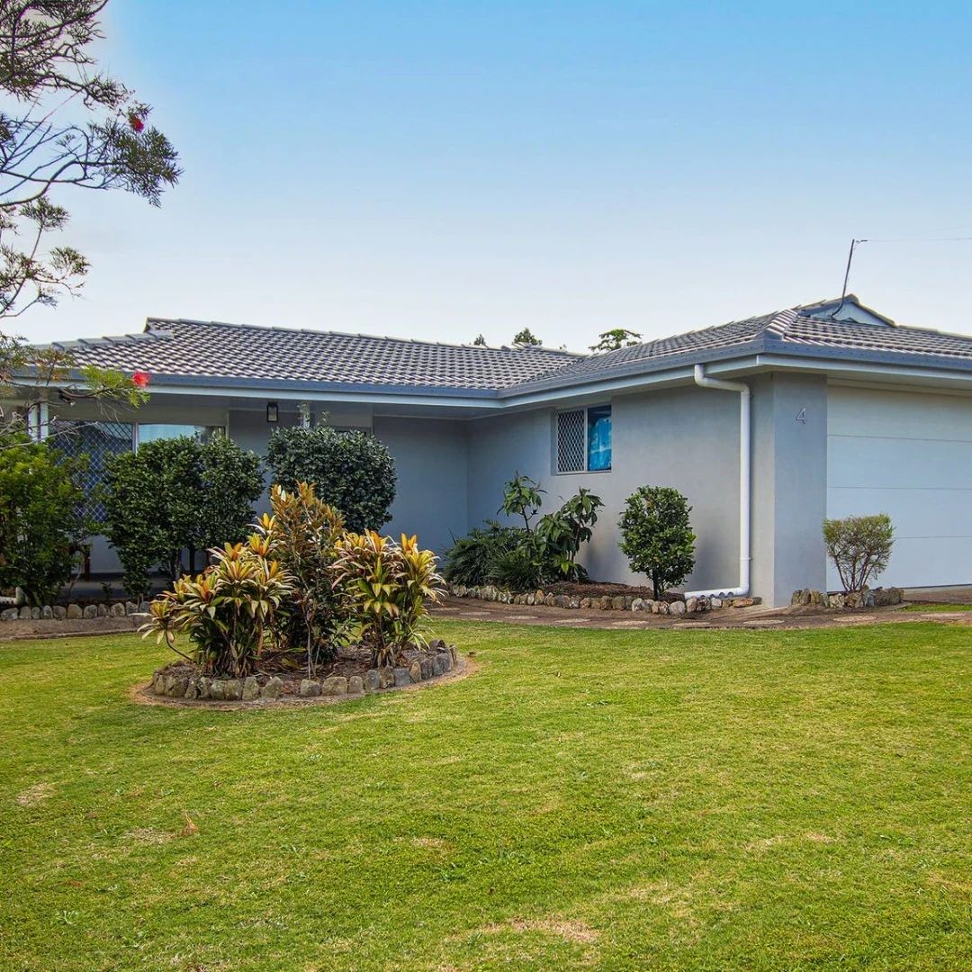 Gray house with garage, lawn, and landscaping.