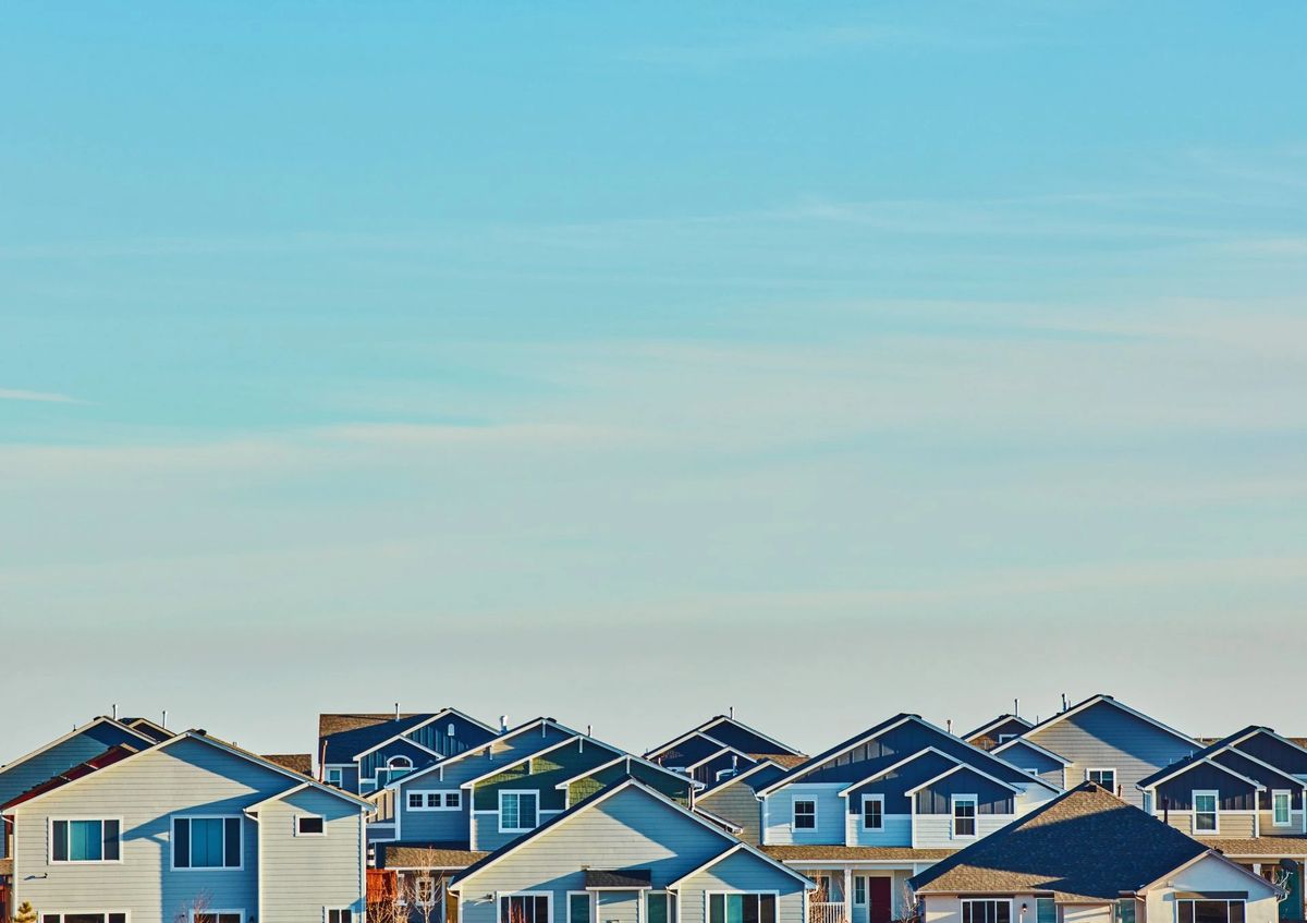 Rows of new suburban houses beneath a clear blue sky