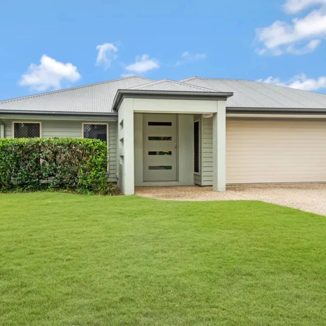 Pale green investment home with a double garage and trimmed lawn on the Gold Coast, Queensland