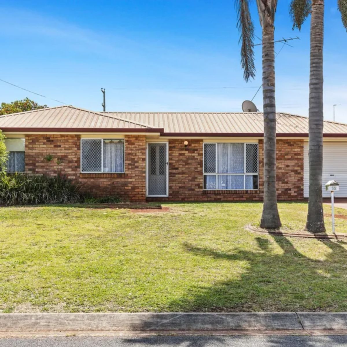 Single-storey brick investment home with palm trees and a garage in Toowoomba, Queensland