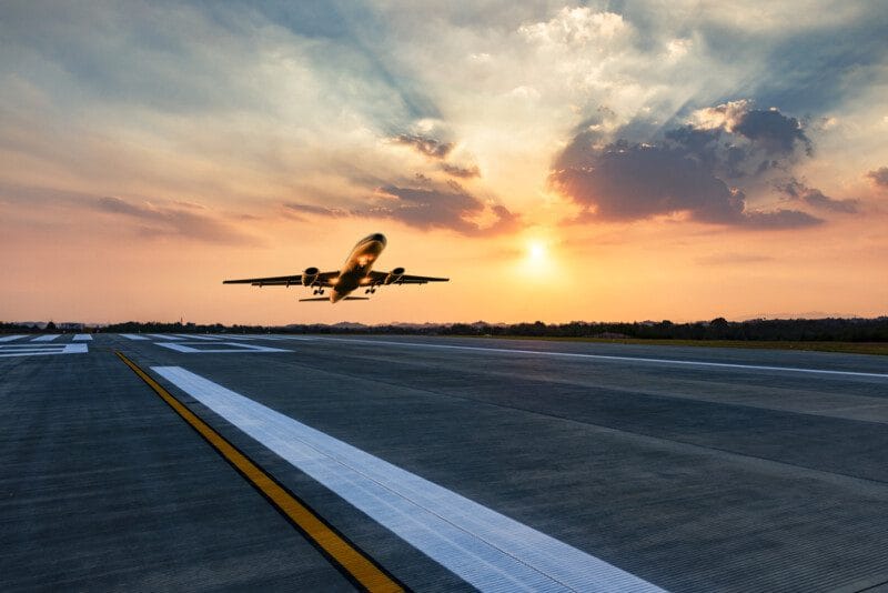 Airplane taking off at sunset on runway