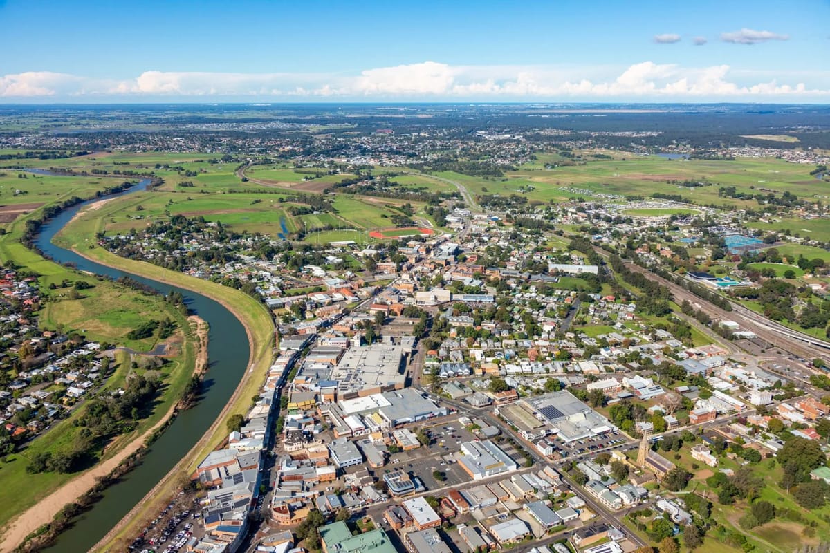 River winds past town with surrounding green fields.