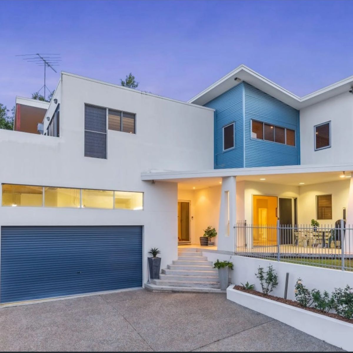 Modern house w/ blue siding, garage, and patio.
