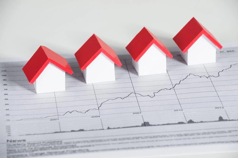 Four model houses on a graph showing upward trend.