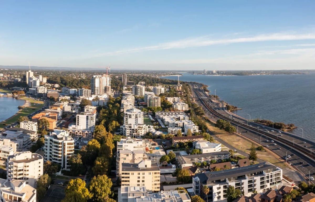 Aerial perspective of buildings and a highway by the water.