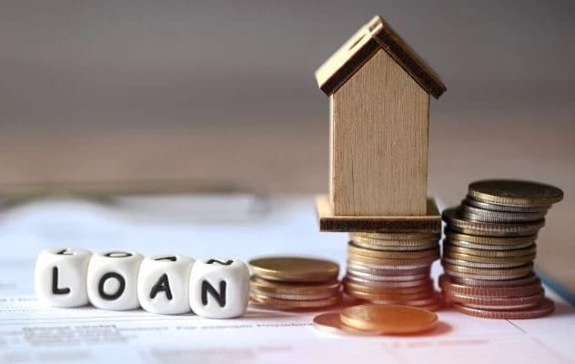 Loan dice, miniature house, and stacks of coins.