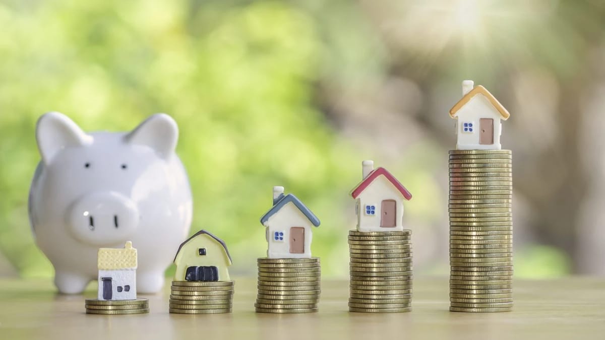 Piggy bank and miniature houses on stacks of coins.