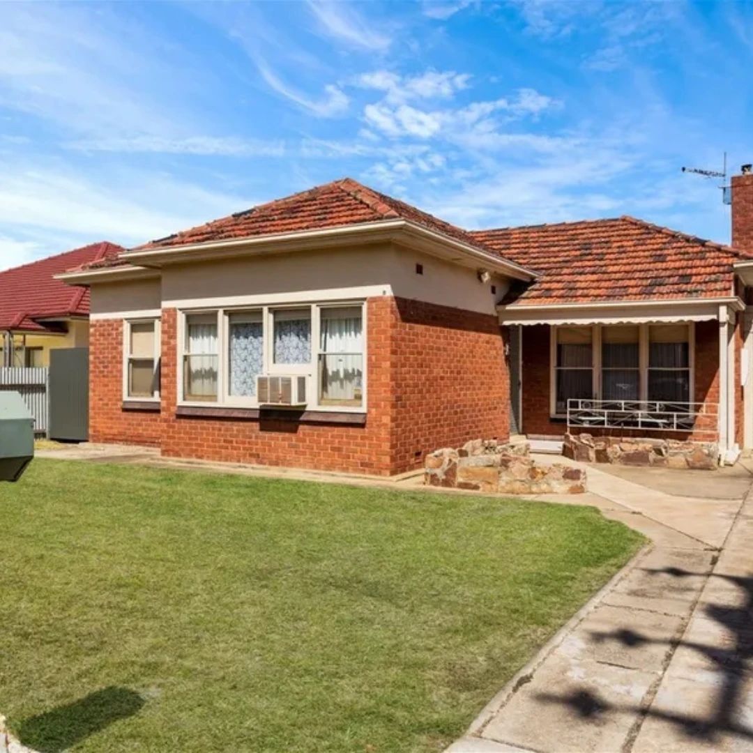 Brick house with tiled roof and green lawn.