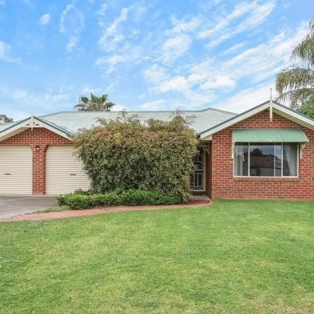 Brick house with two garages and a large bush.