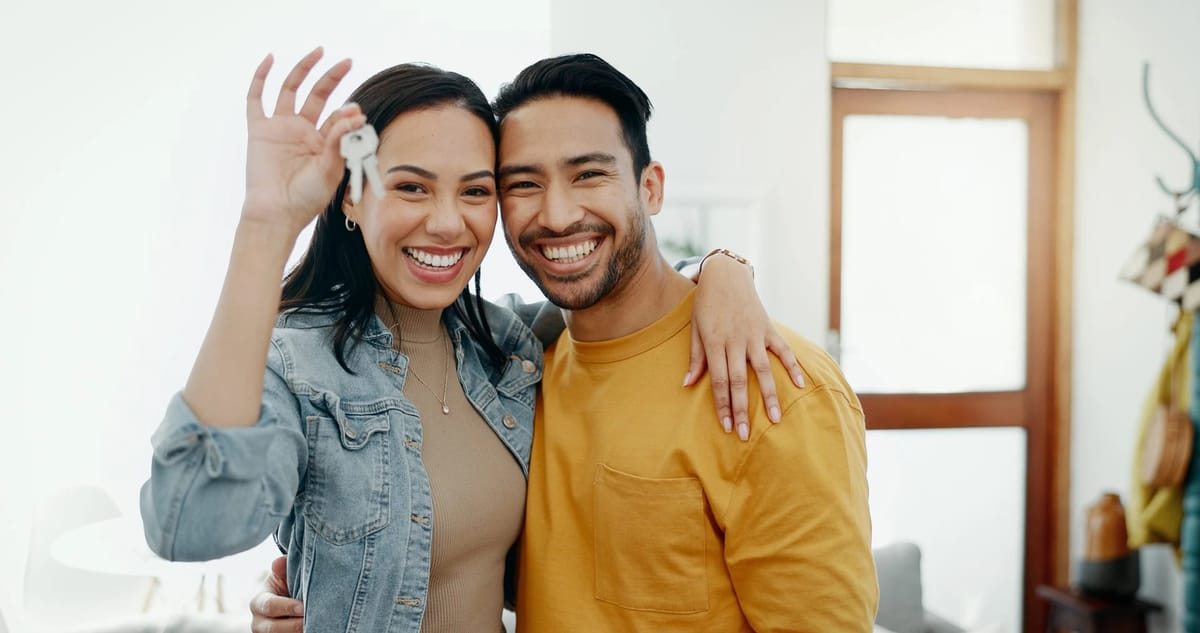 Couple with keys to new home, smiling broadly.