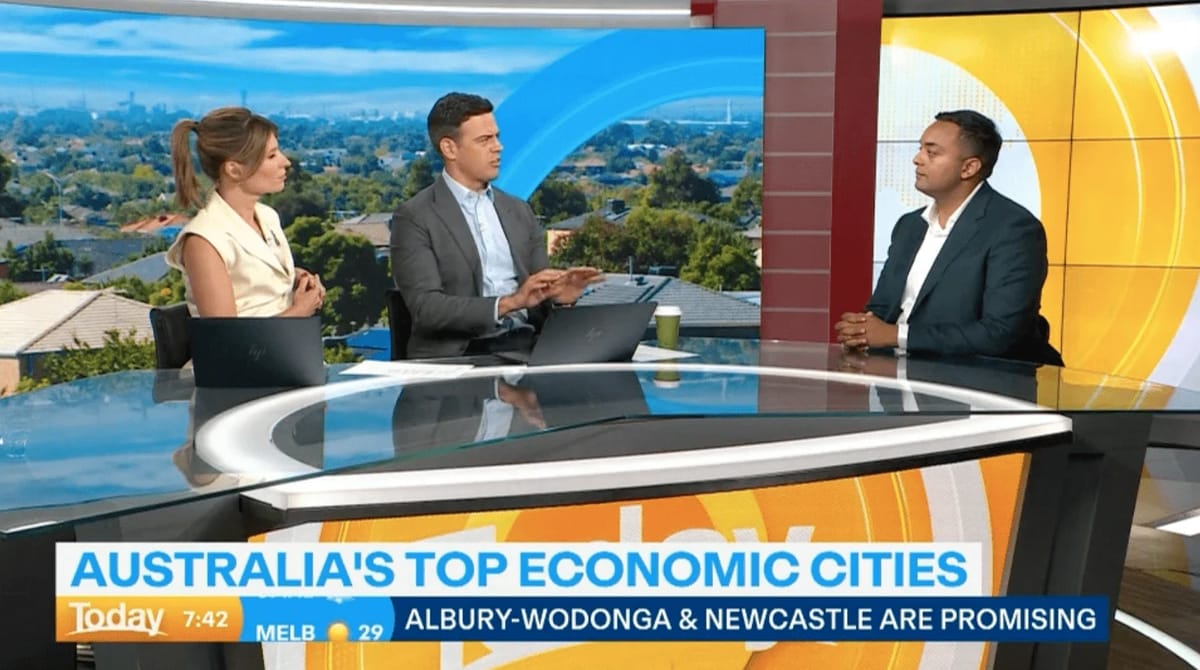 News anchors discussing Australian economic cities on TV.