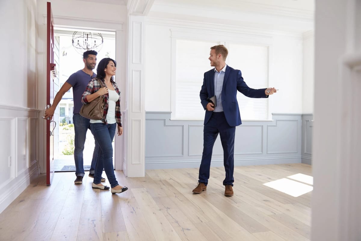 Realtor shows home to a couple entering through open door.
