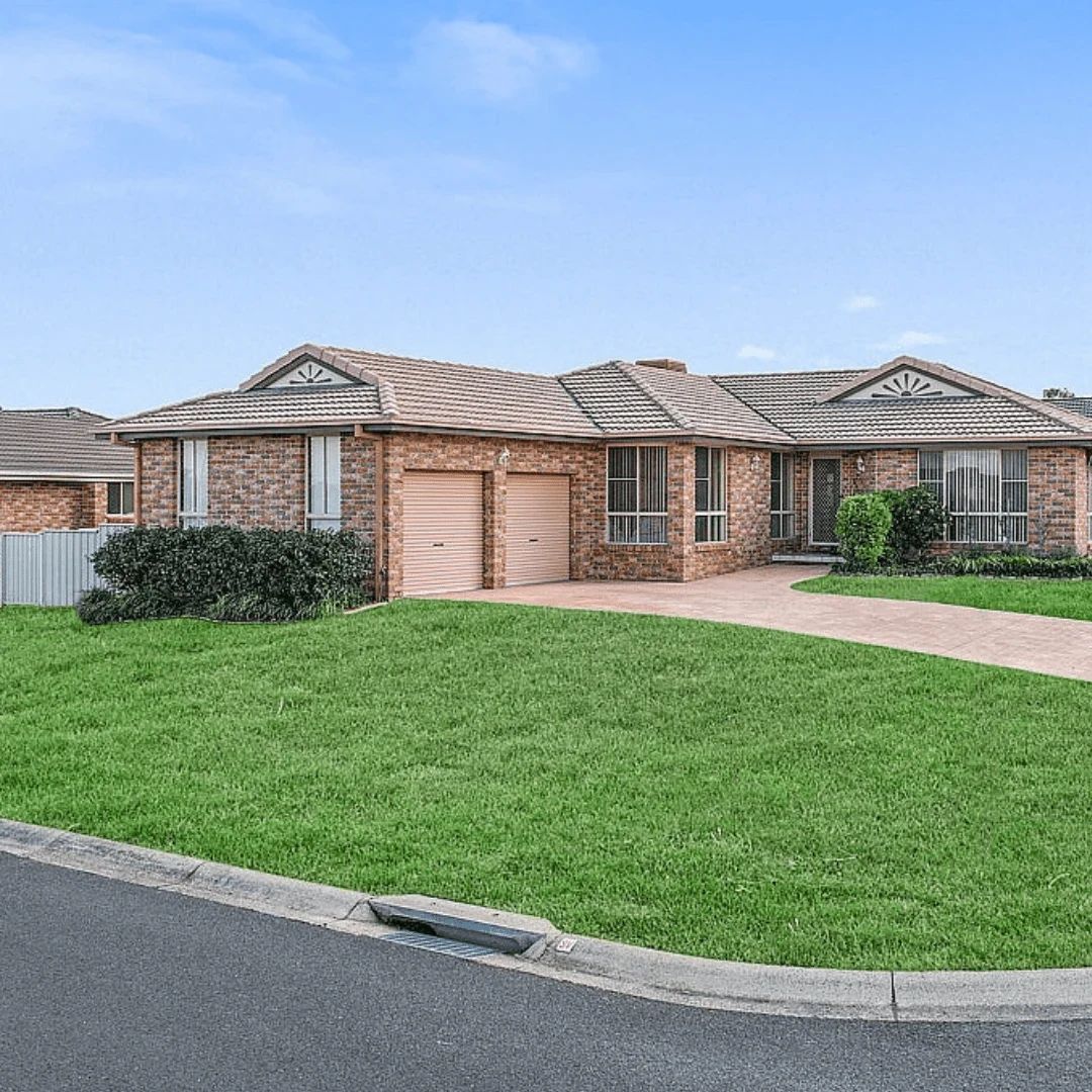 Brick house with two garage doors and a green lawn.