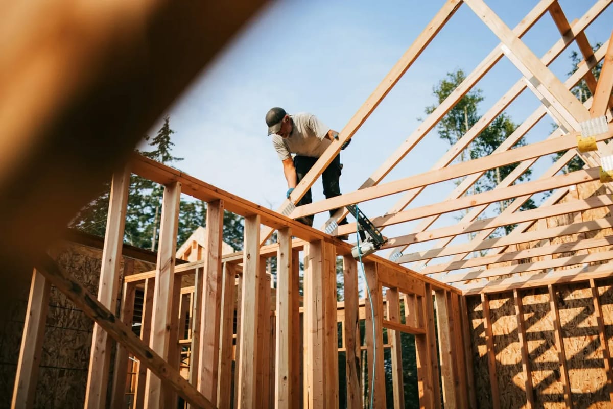 Construction worker framing roof with nail gun