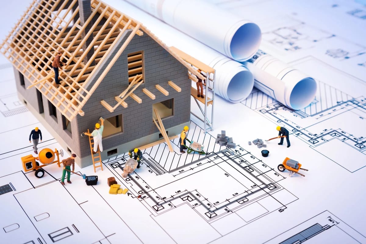 Miniature construction scene on blueprints with model house.