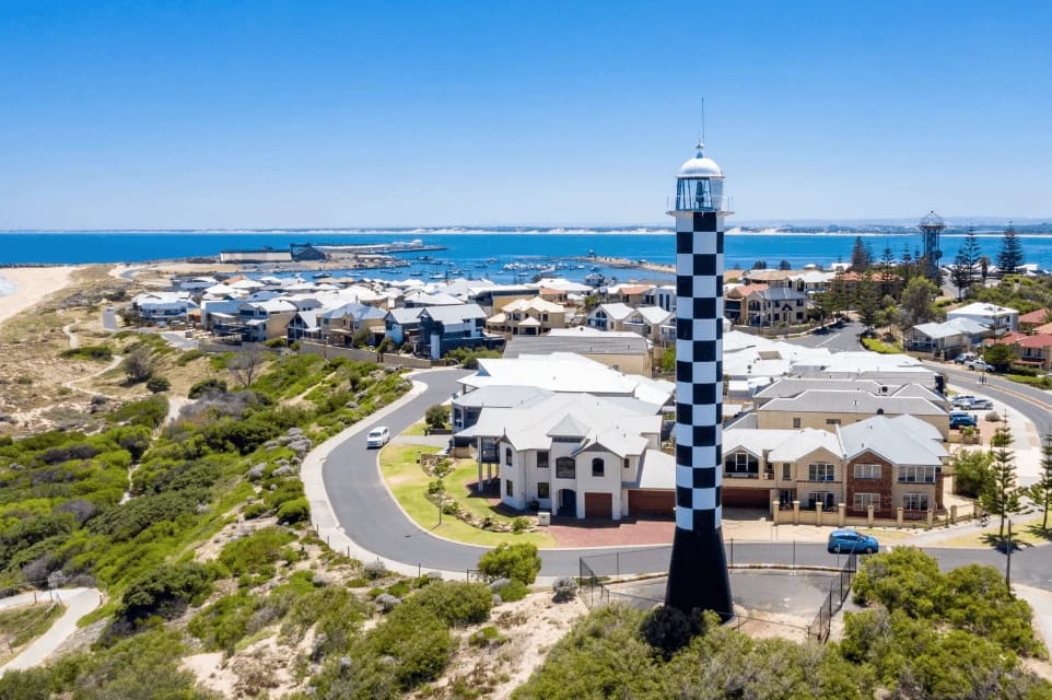 Black and white checkered lighthouse near coastal homes.