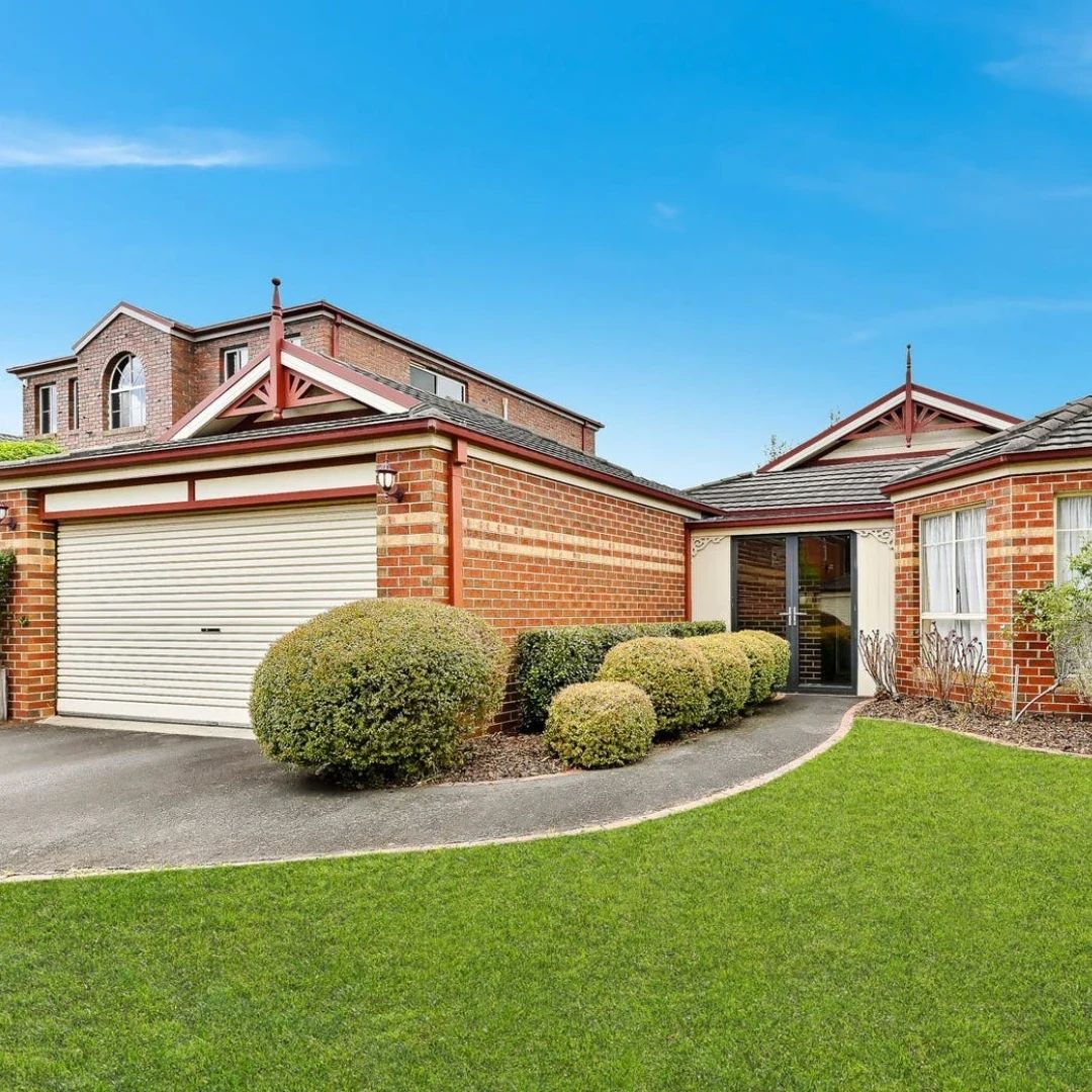 Red brick home with garage and manicured bushes
