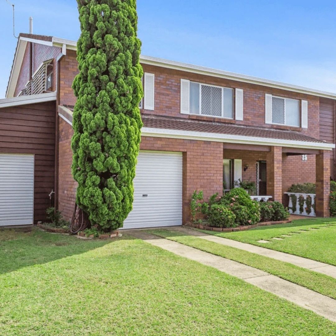 Brick house with green tree and garage.