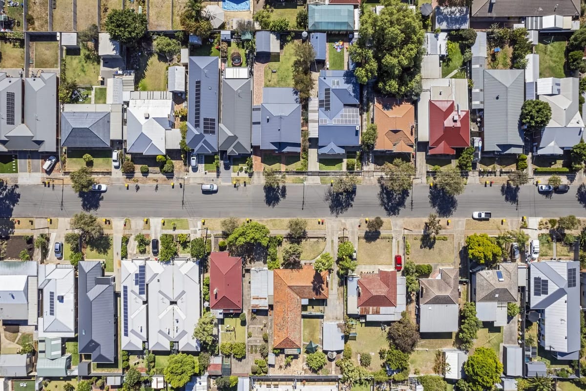 Aerial view of a suburban street with houses and cars.