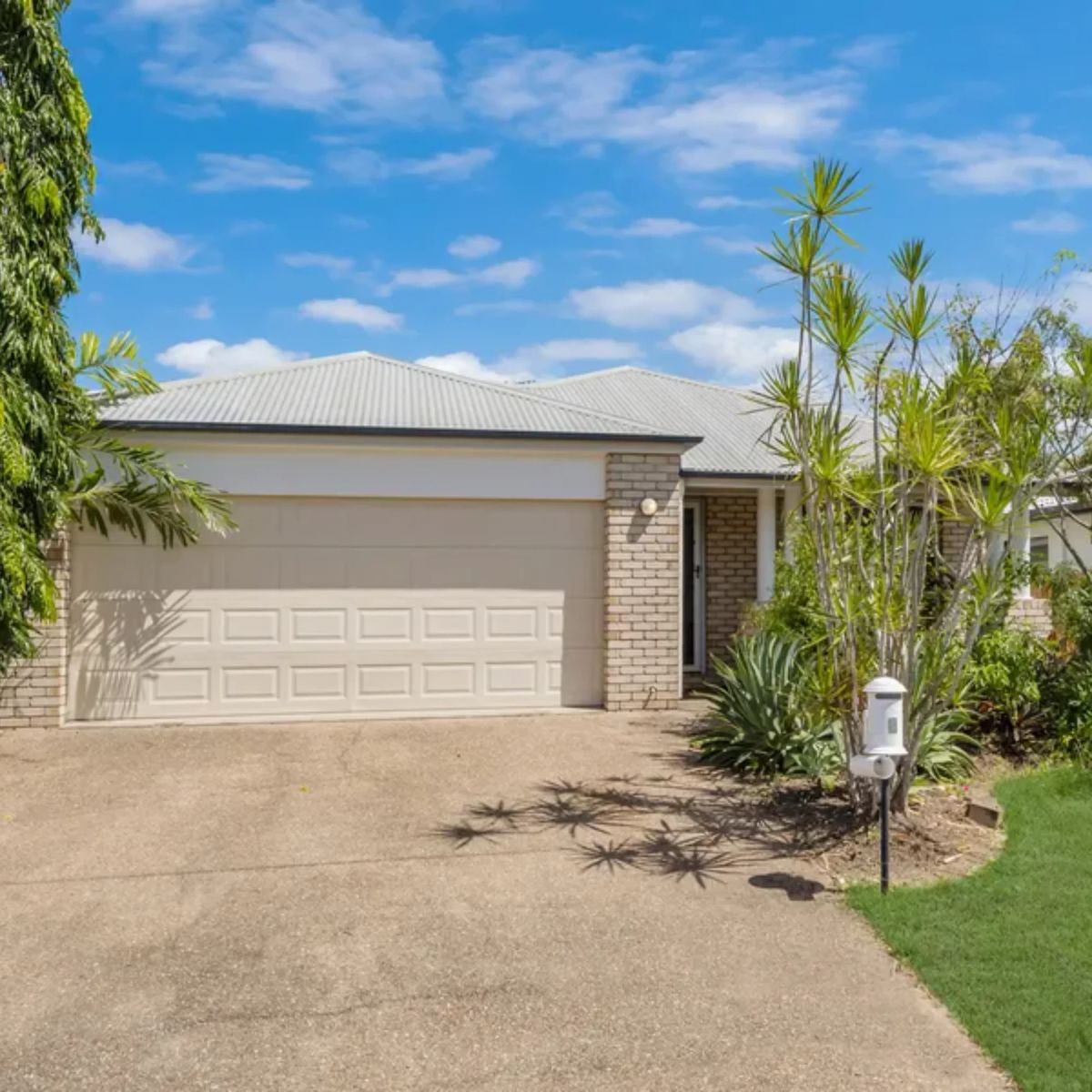 Pale brick investment home with a double garage and tropical garden in Townsville, Queensland