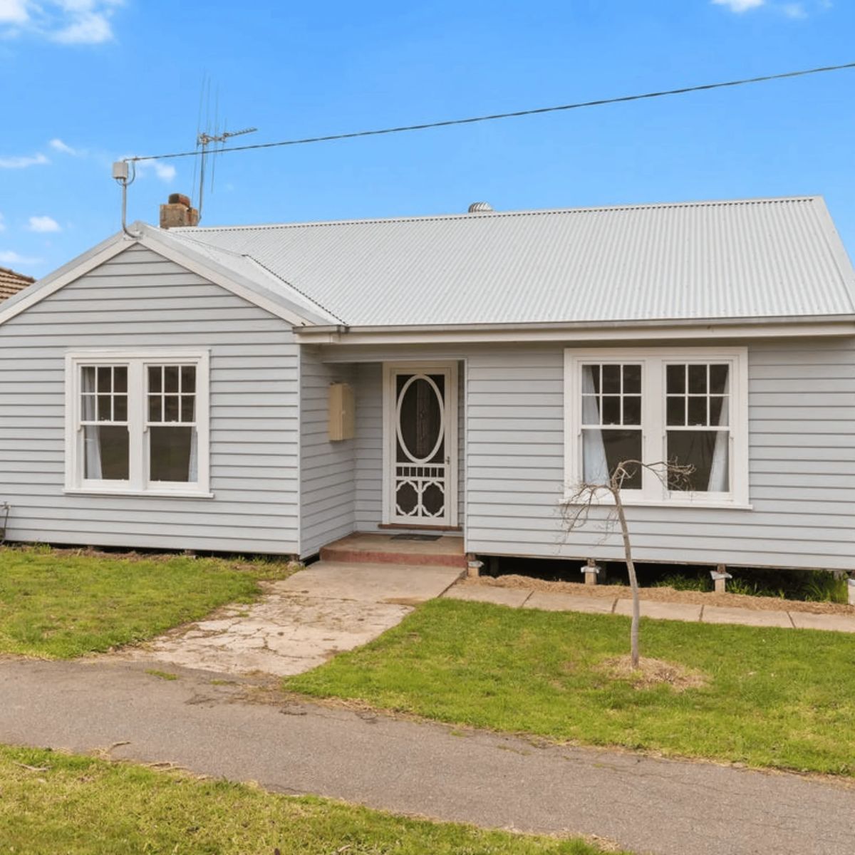 Light blue house with white trim and a metal roof.