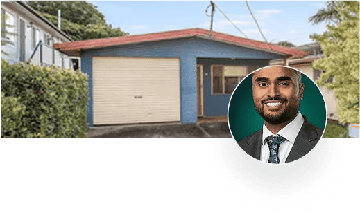 Man in suit next to blue house with garage