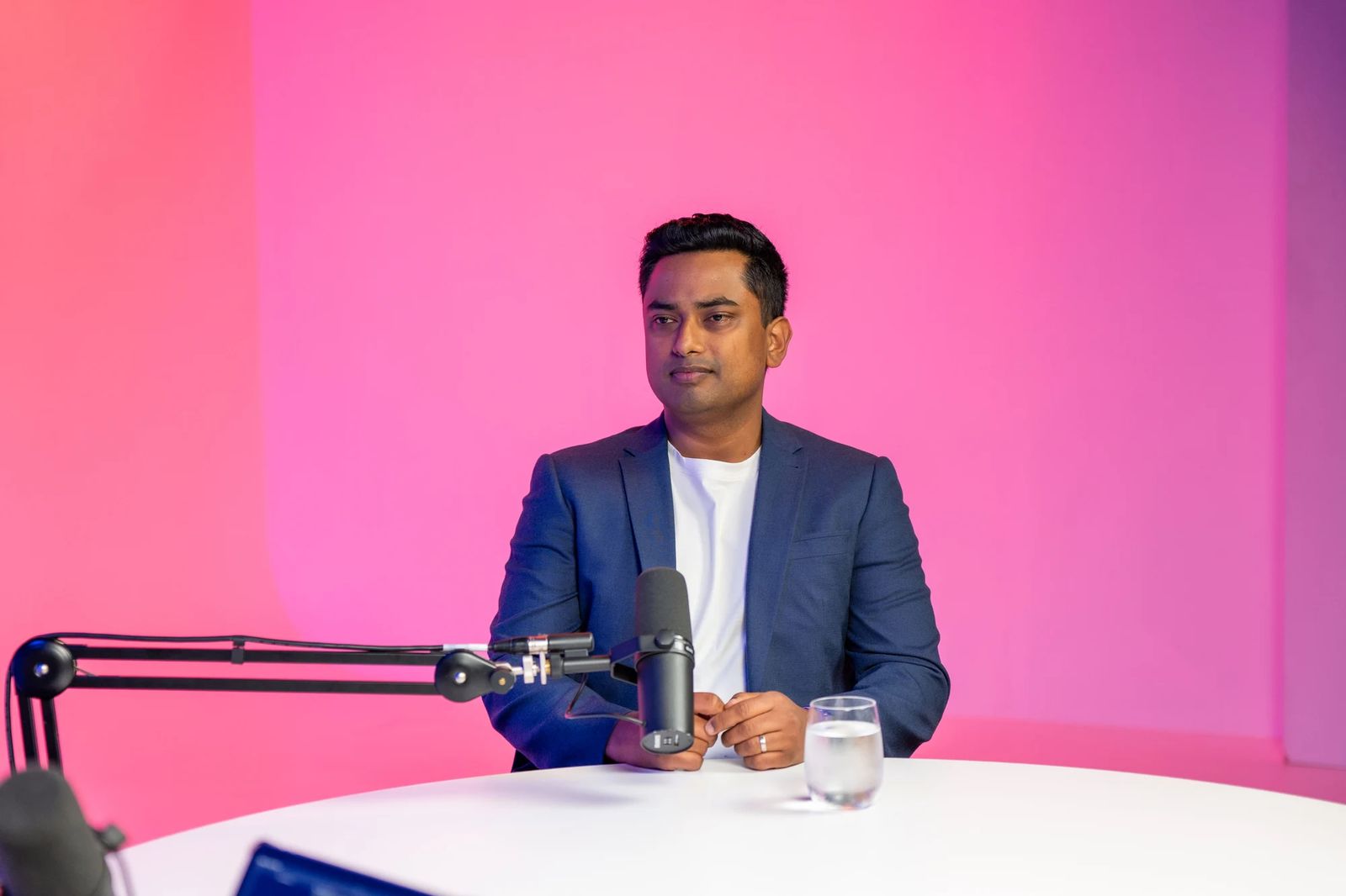 Man in blue suit at table with microphone