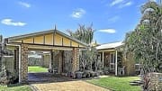 Investment property with a gabled, stone pillared front porch and landscaped garden