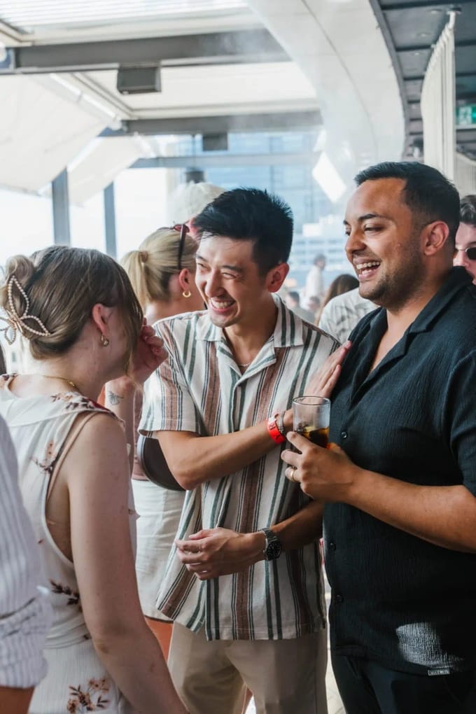 Three people laughing and talking at an event.