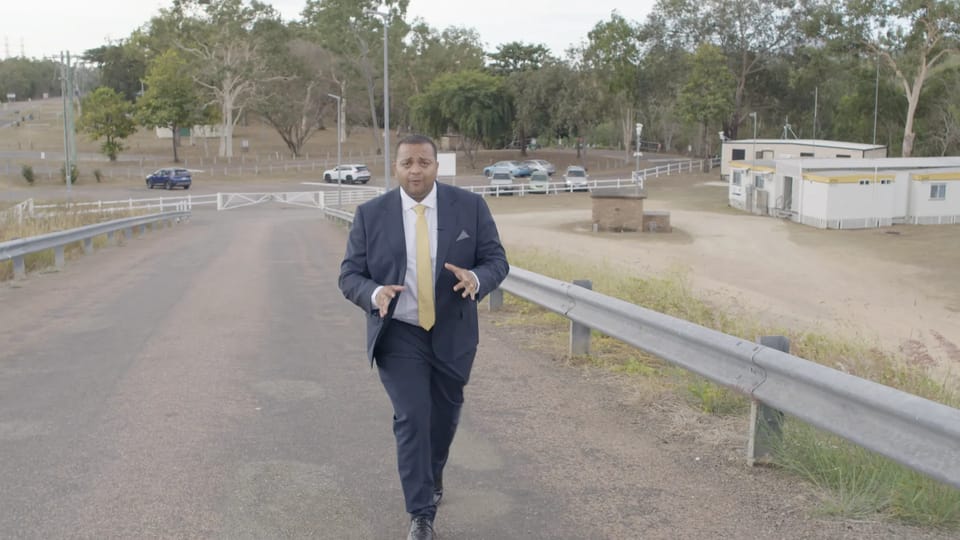 Arjun Paliwal walking along the approach road to Ross River Dam, past demountable huts and gum trees