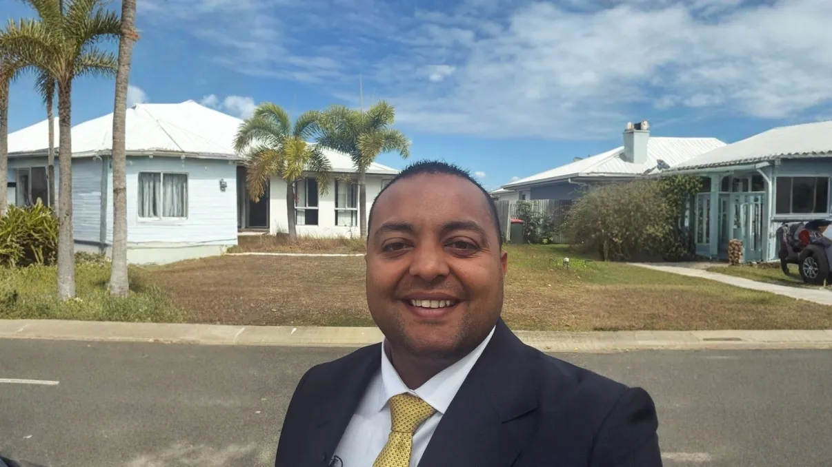 Arjun Paliwal in a suit on a Townsville street, in front of a house with palm trees, the photo sent with his note.