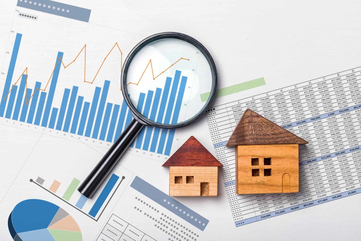 Magnifying glass over property market charts and model houses