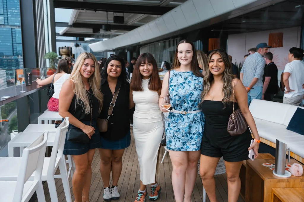 Five women stand on a rooftop patio.
