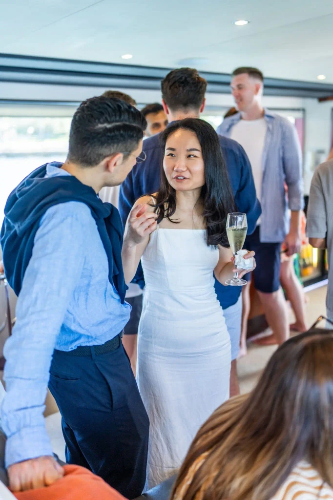 Woman in white dress holding champagne, talking to man.